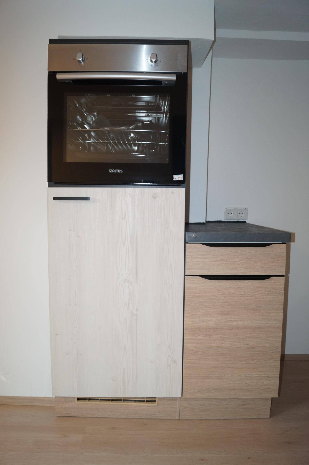 Eingebauter Backofen in einer modernen Küche mit hellen Holzschränken und Arbeitsplatte.