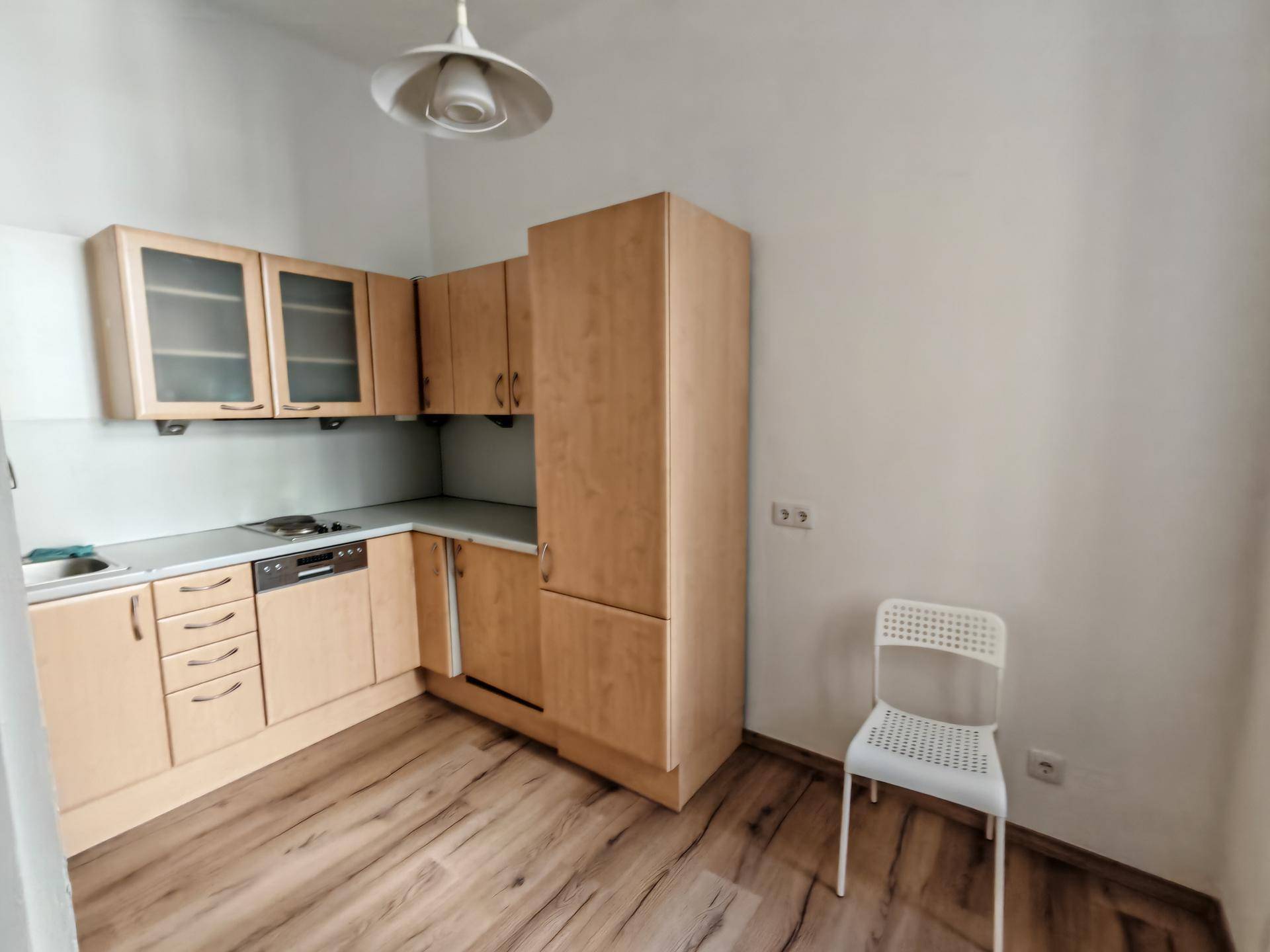 Funktionale Küche mit hellen Holzschränken, integriertem Geschirrspüler und modernem Laminatboden.