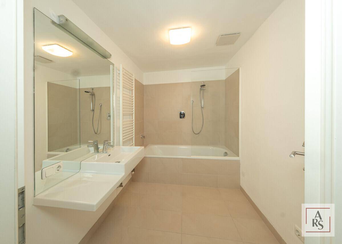 Modernes Badezimmer mit Badewanne, Doppelwaschbecken und großem Spiegel.
