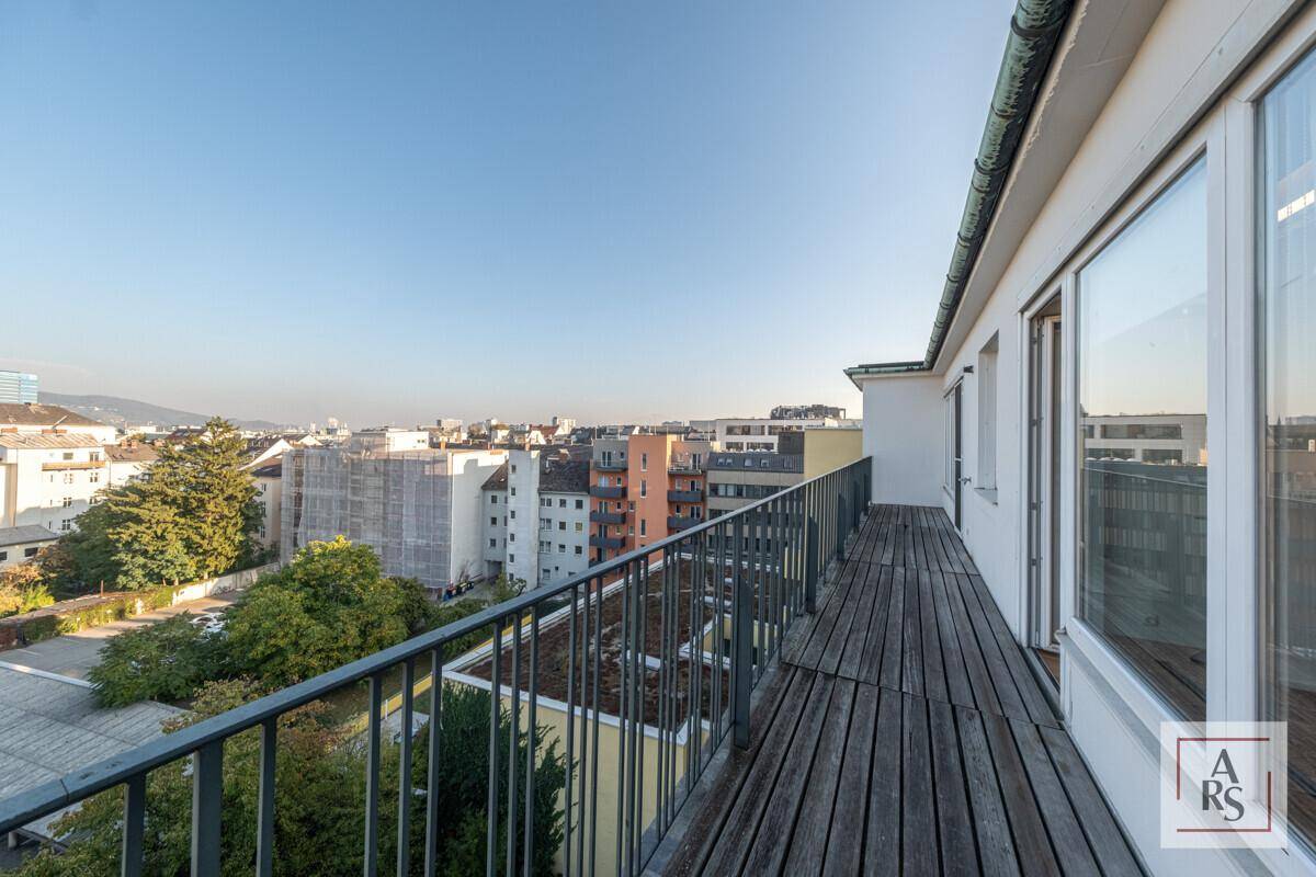 Langer Balkon mit Holzboden und Metallgeländer bietet einen weiten Blick über die Stadt.