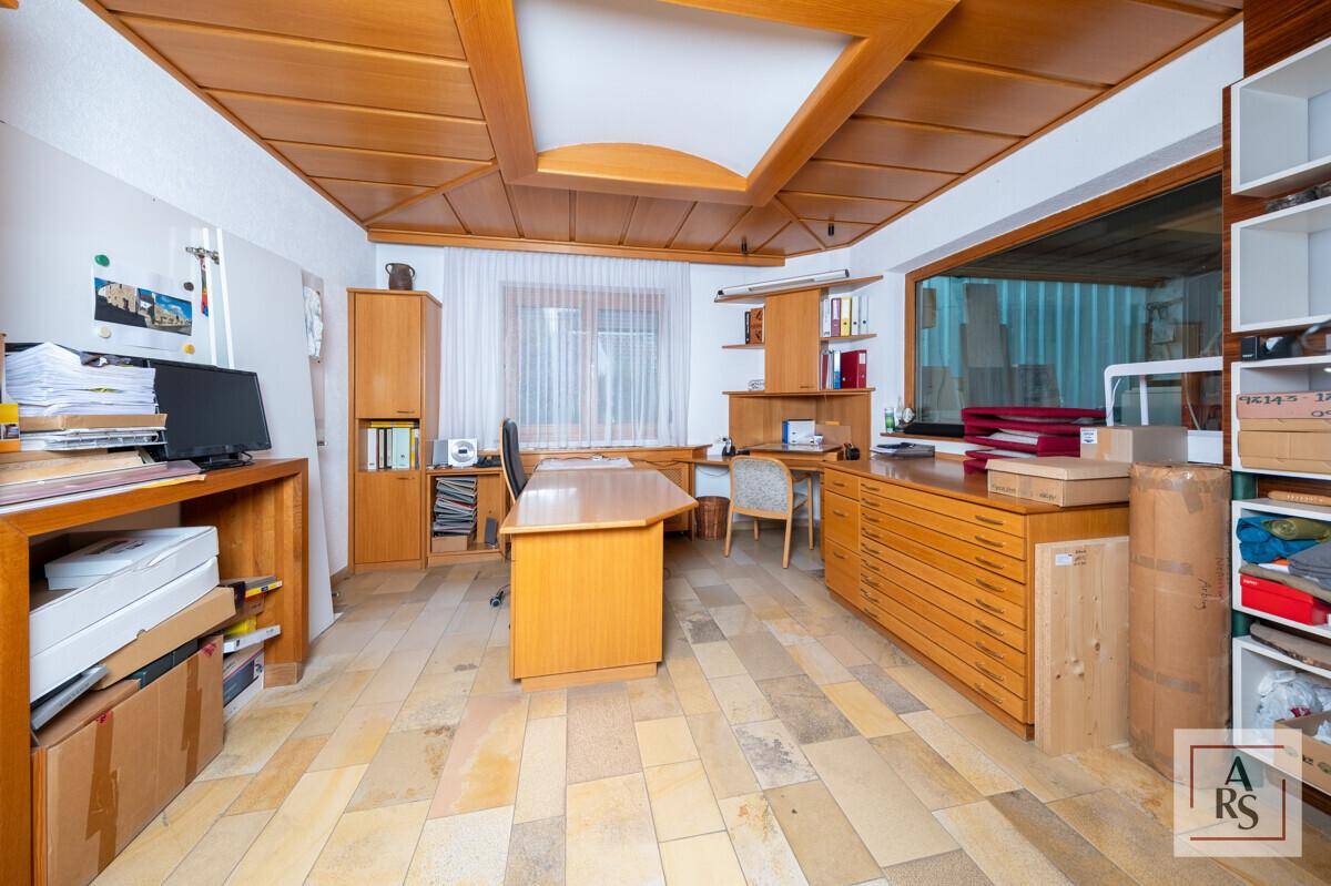 Geräumiges Büro mit Holzmöbeln, Schreibtisch und Stauraum, ausgestattet mit Steinfliesenboden und Holzdecke.