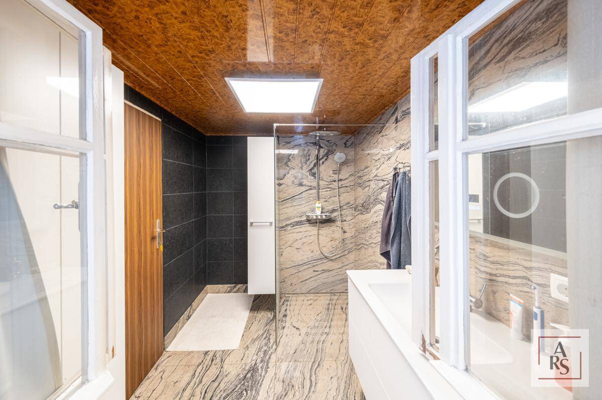 Elegantes Badezimmer mit begehbarer Dusche, Marmorfliesen und dunklen Akzentwänden.
