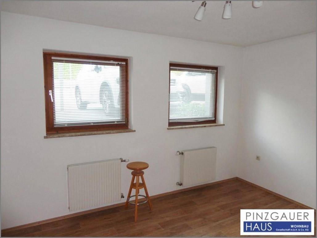 Helles Zimmer mit zwei Fenstern, Holzrahmen und Heizkörpern unter den Fenstern, bereit zur individuellen Gestaltung.