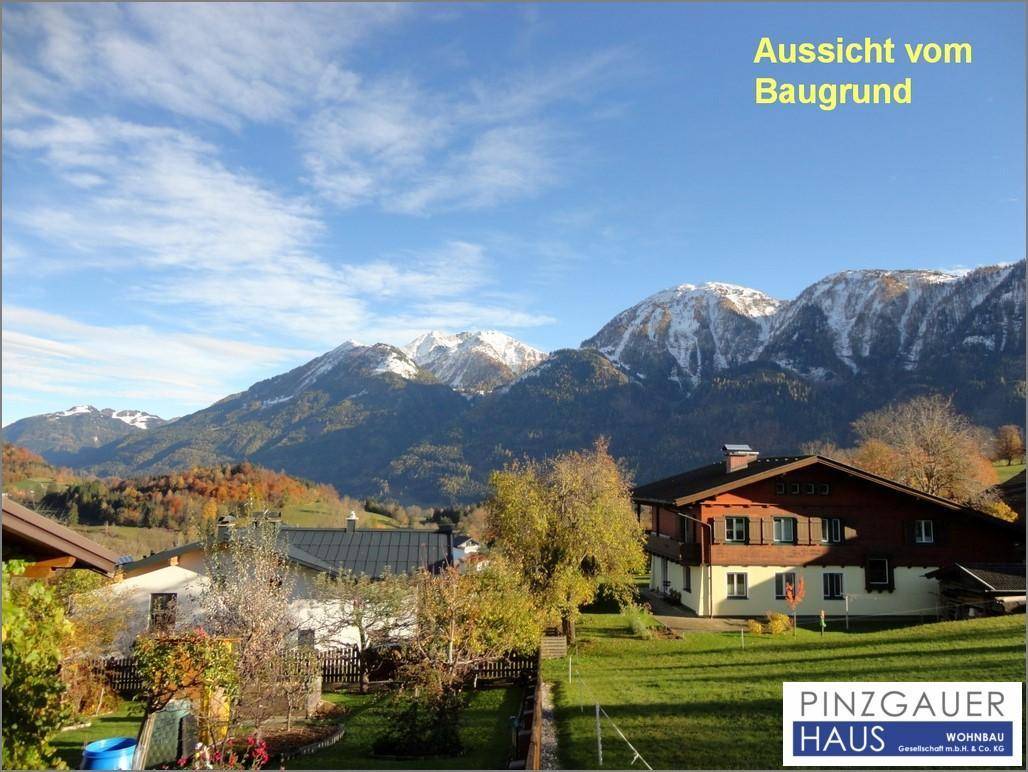 Panoramablick auf schneebedeckte Berge und traditionelle Häuser in der ländlichen Umgebung an einem sonnigen Tag.