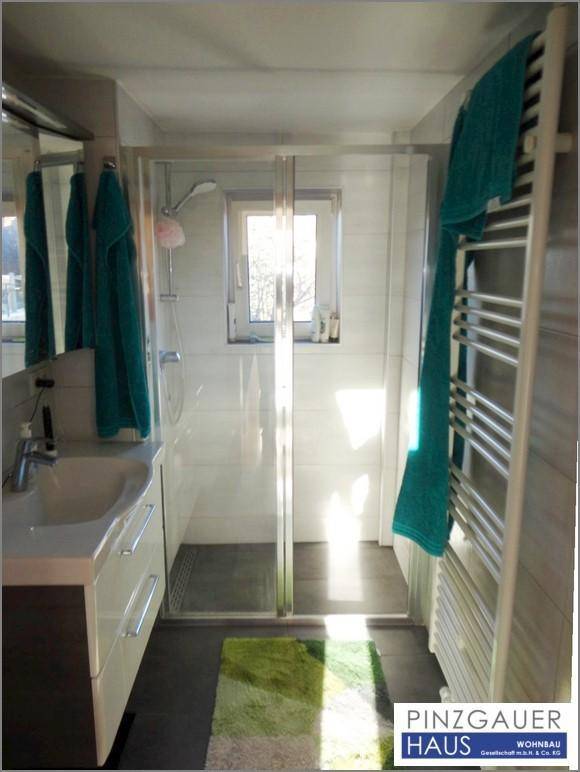Modernes Badezimmer mit ebenerdiger Dusche, Waschbecken und beheiztem Handtuchhalter.