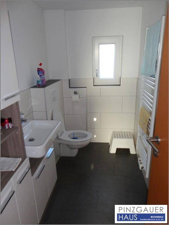 Modernes Gäste-WC mit dunklen Fliesen, wandhängendem WC und beheiztem Handtuchhalter.