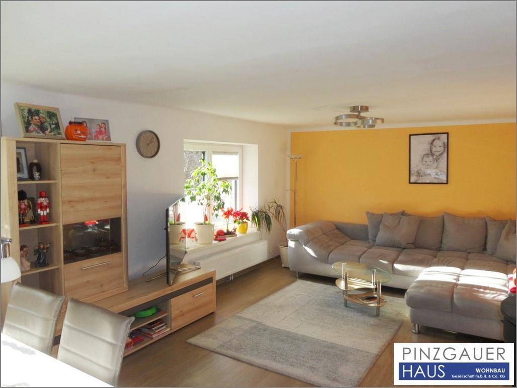 Gemütliches Wohnzimmer mit großem Ecksofa, hellem Laminatboden und gelber Akzentwand.