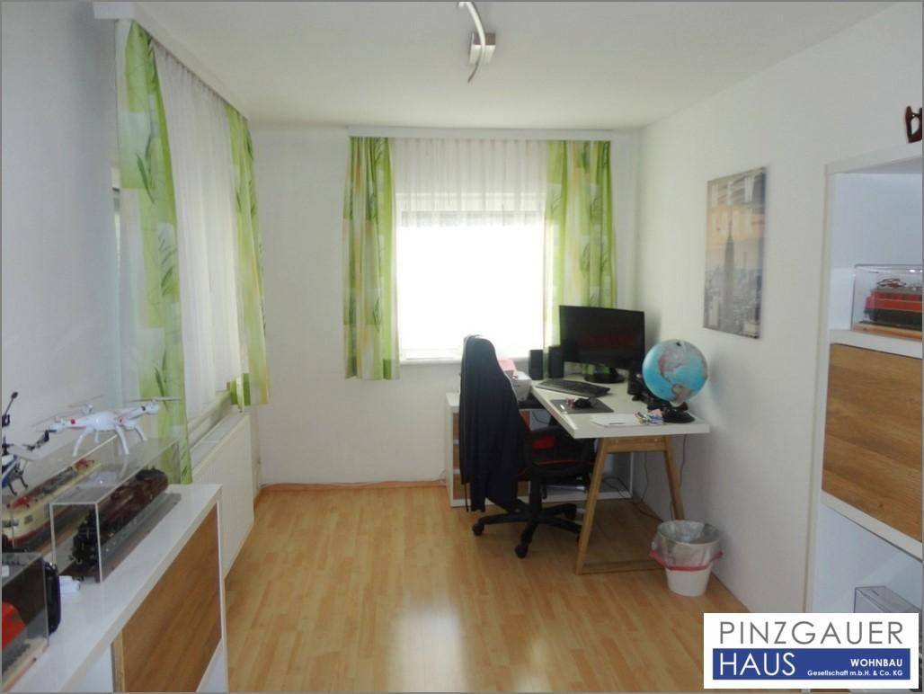 Funktionales Arbeitszimmer mit Schreibtisch, Bürostuhl und hellem Laminatboden.