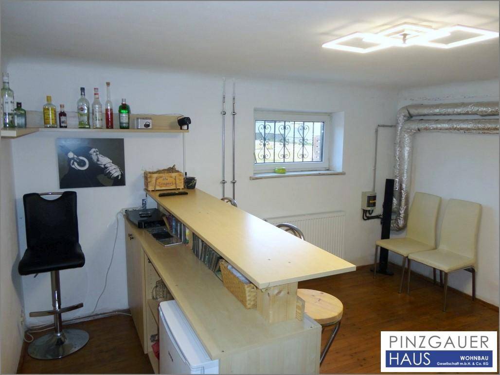 Kellerraum mit Bar, Sitzgelegenheiten und einem Fenster, ideal für gesellige Abende.