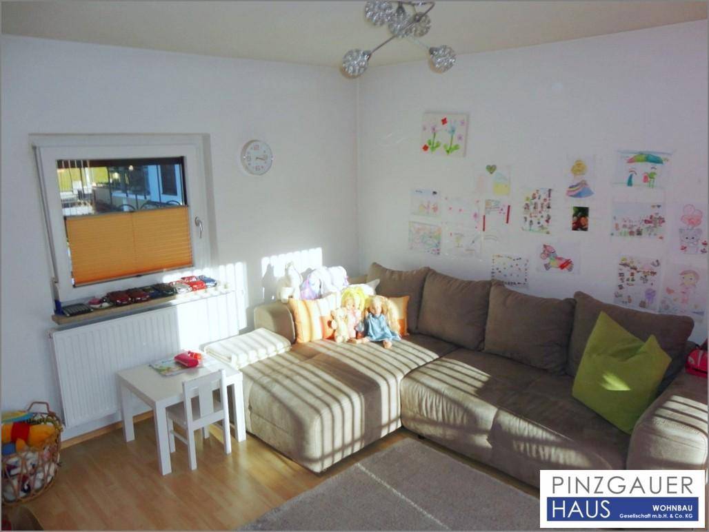 Gemütlicher Wohnbereich mit Ecksofa, Laminatboden und viel natürlichem Licht durch das Fenster.