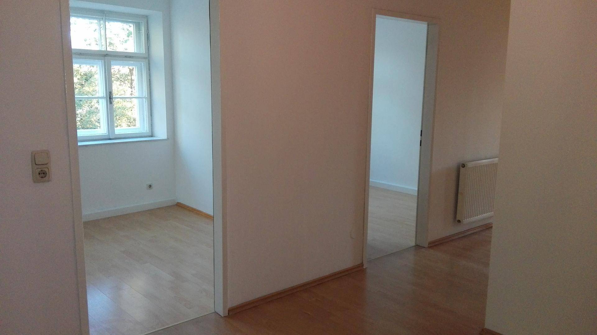 Heller Flur mit Holzboden und offenen Türen, die zu weiteren Zimmern führen.