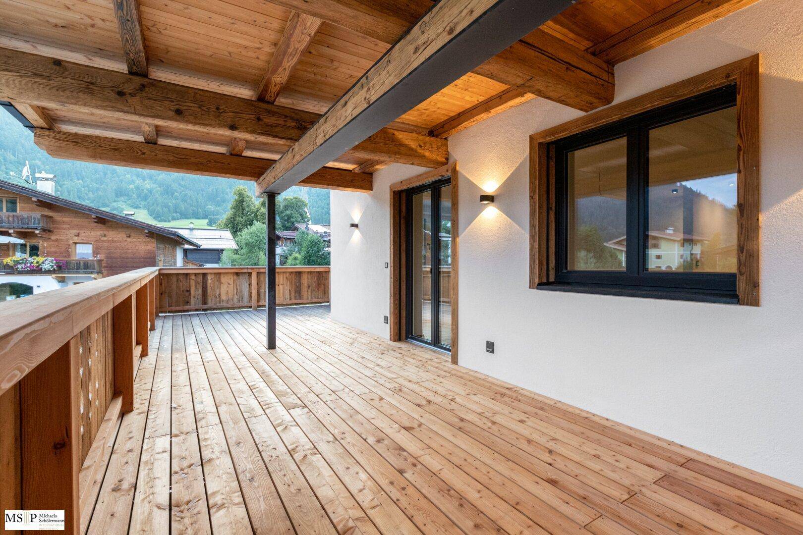 Weitläufiger Holzbalkon mit Bergblick und traditionellem Holzgeländer, ideal für alpine Entspannung.