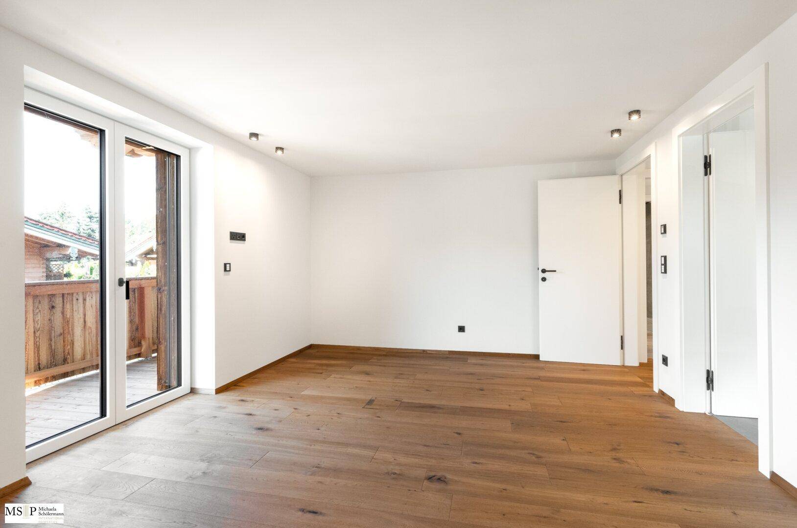 Helles, leeres Zimmer mit Holzboden und direktem Zugang zu einem Balkon, bereit zur individuellen Gestaltung.