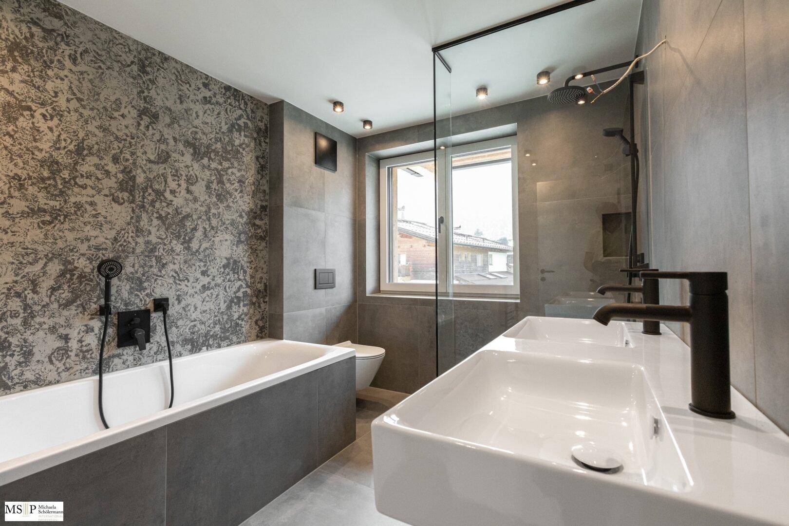 Elegantes Badezimmer mit zwei Waschbecken, Badewanne und Duschbereich, ausgestattet mit modernen Armaturen.
