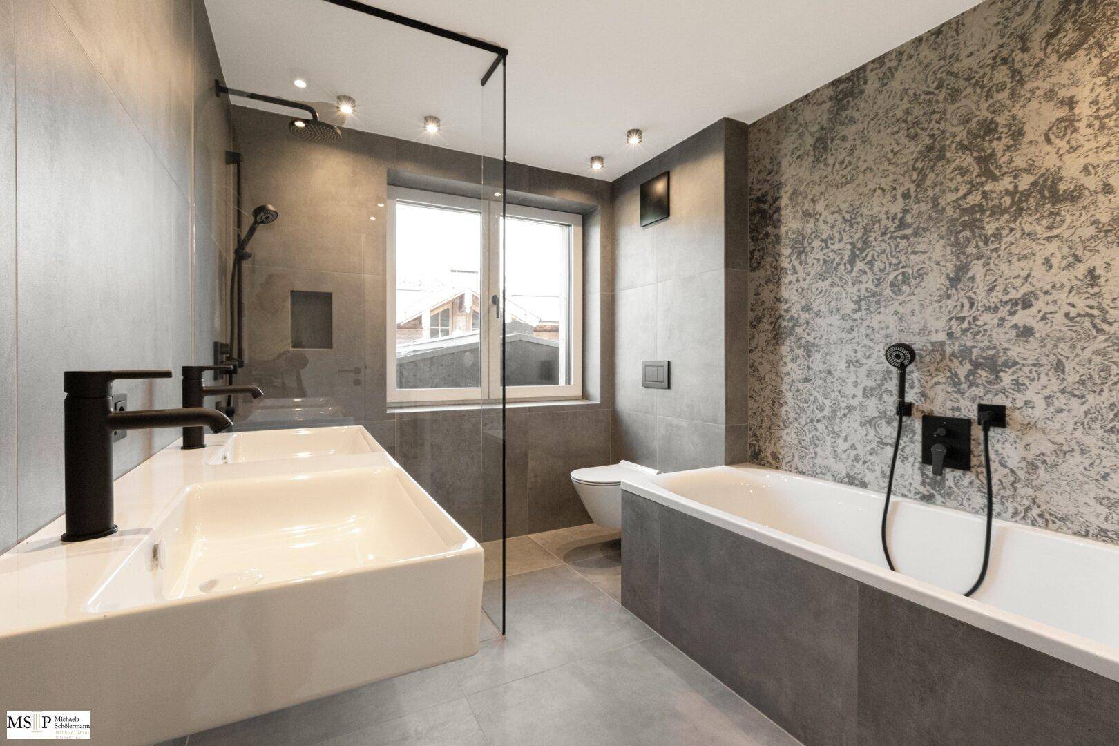 Modernes Badezimmer mit Doppelwaschbecken, Badewanne, Duschbereich und Fenster, in Grautönen gehalten.