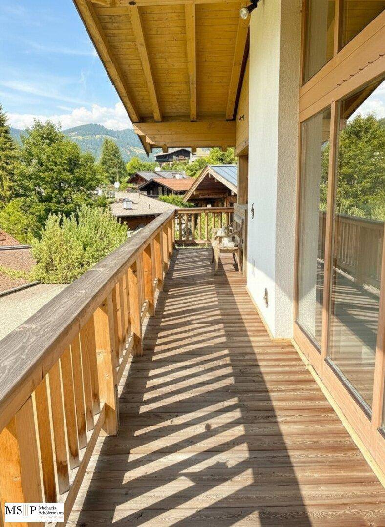 Langer Holzbalkon mit Bergblick und viel Sonnenschein, ideal zum Entspannen im Freien.
