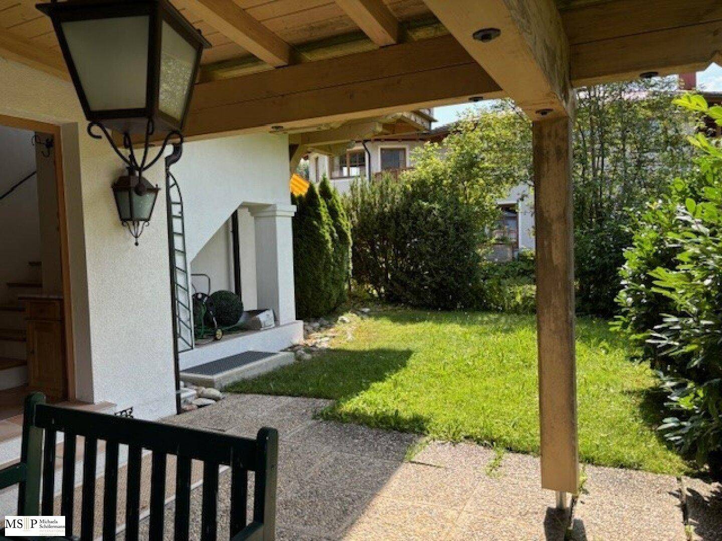 Kleiner Gartenbereich mit Rasenfläche und überdachtem Sitzplatz, ideal für entspannte Stunden.