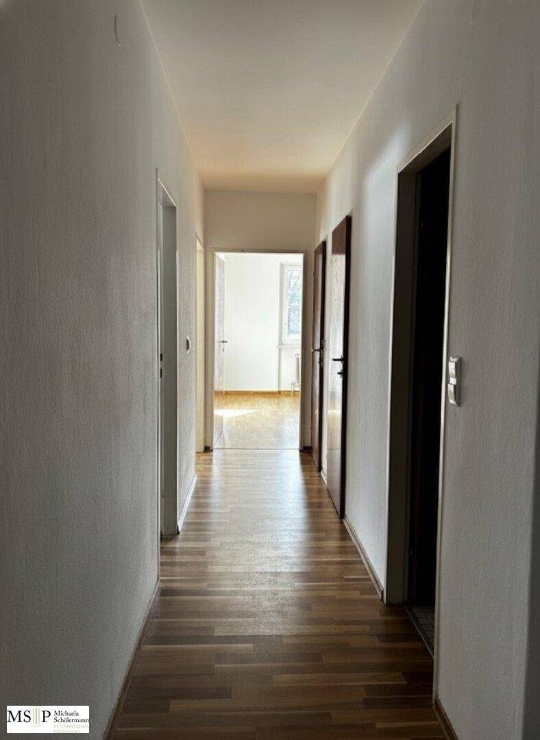 Langer, heller Flur mit Holzparkettboden und mehreren Türen zu angrenzenden Räumen.