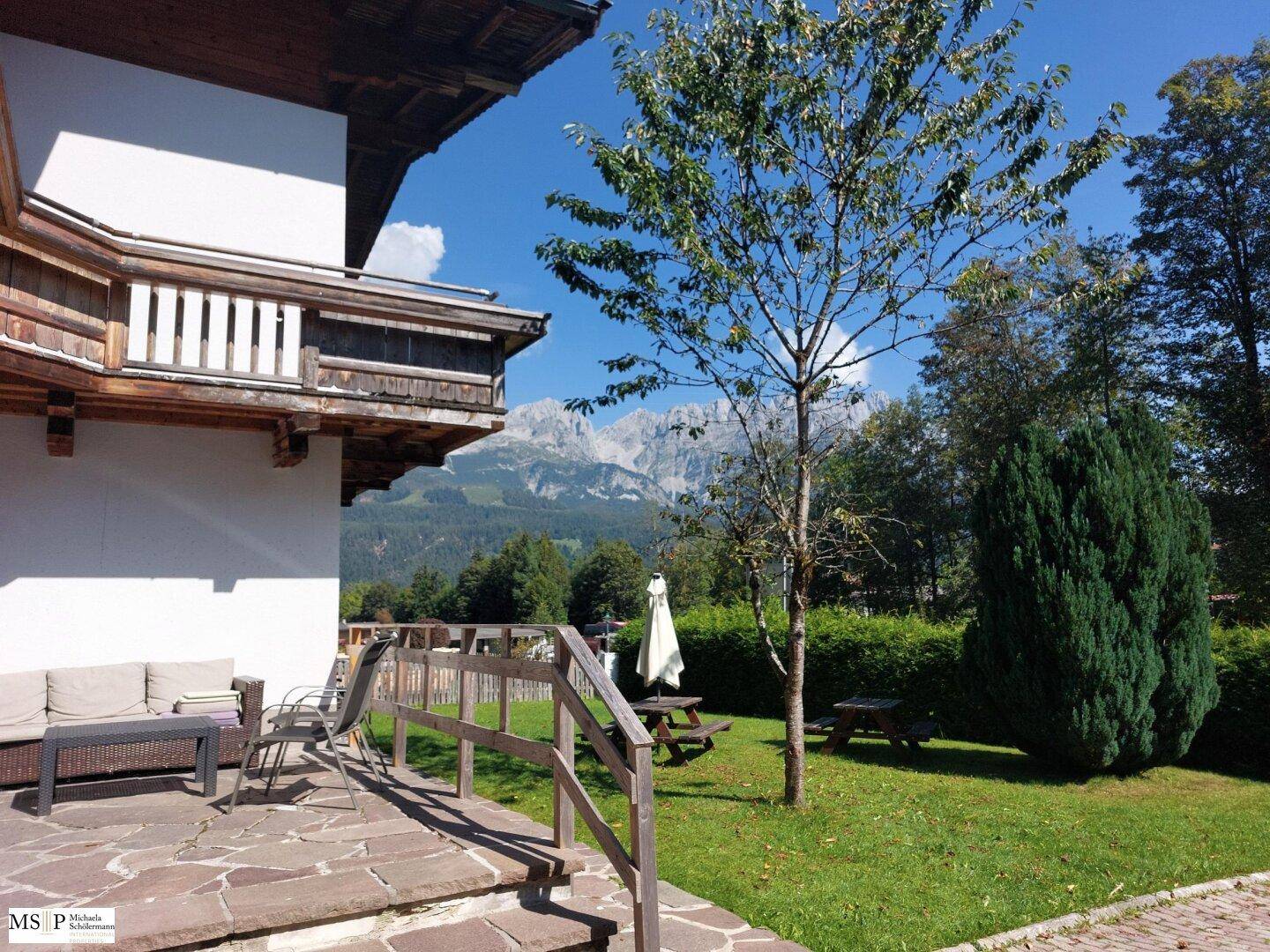 Sonnige Terrasse mit Gartenmöbeln und einem beeindruckenden Panoramablick auf die umliegenden Berge.