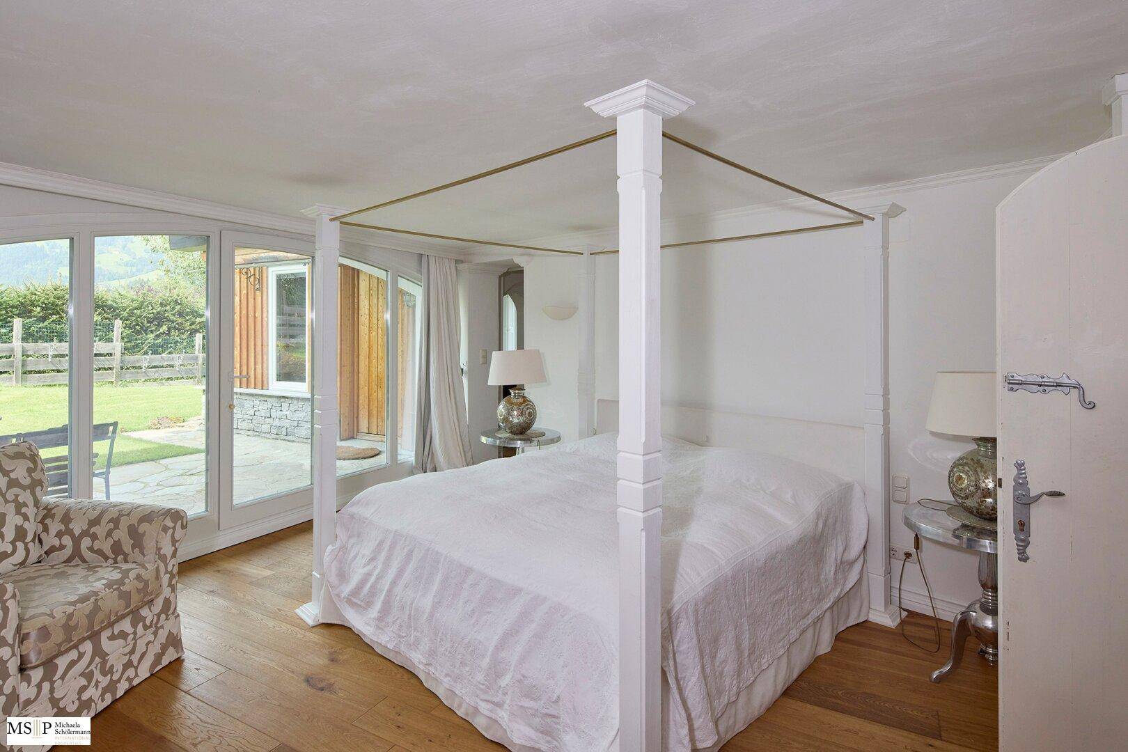 Helles Schlafzimmer mit Himmelbett, Holzboden und direktem Zugang zur Außenterrasse.