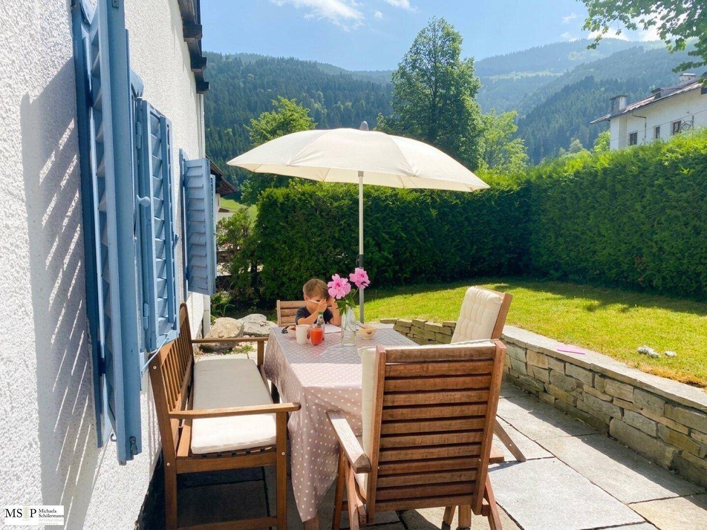 Gemütliche Terrasse mit Esstisch, Sonnenschirm und herrlichem Bergblick ins Grüne.