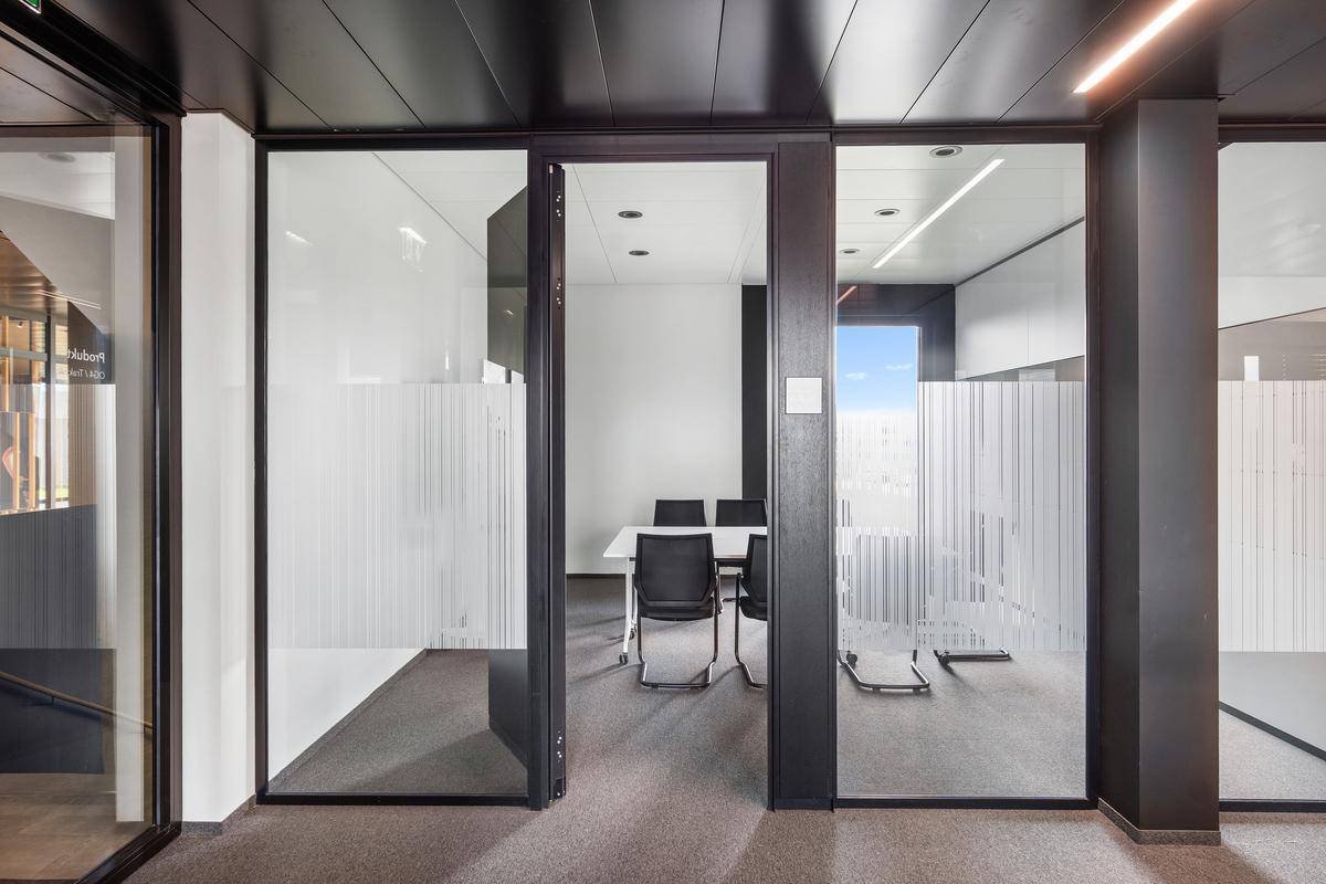 Heller Besprechungsraum mit Glastüren, modernem Tisch und Stühlen, ideal für produktive Meetings.