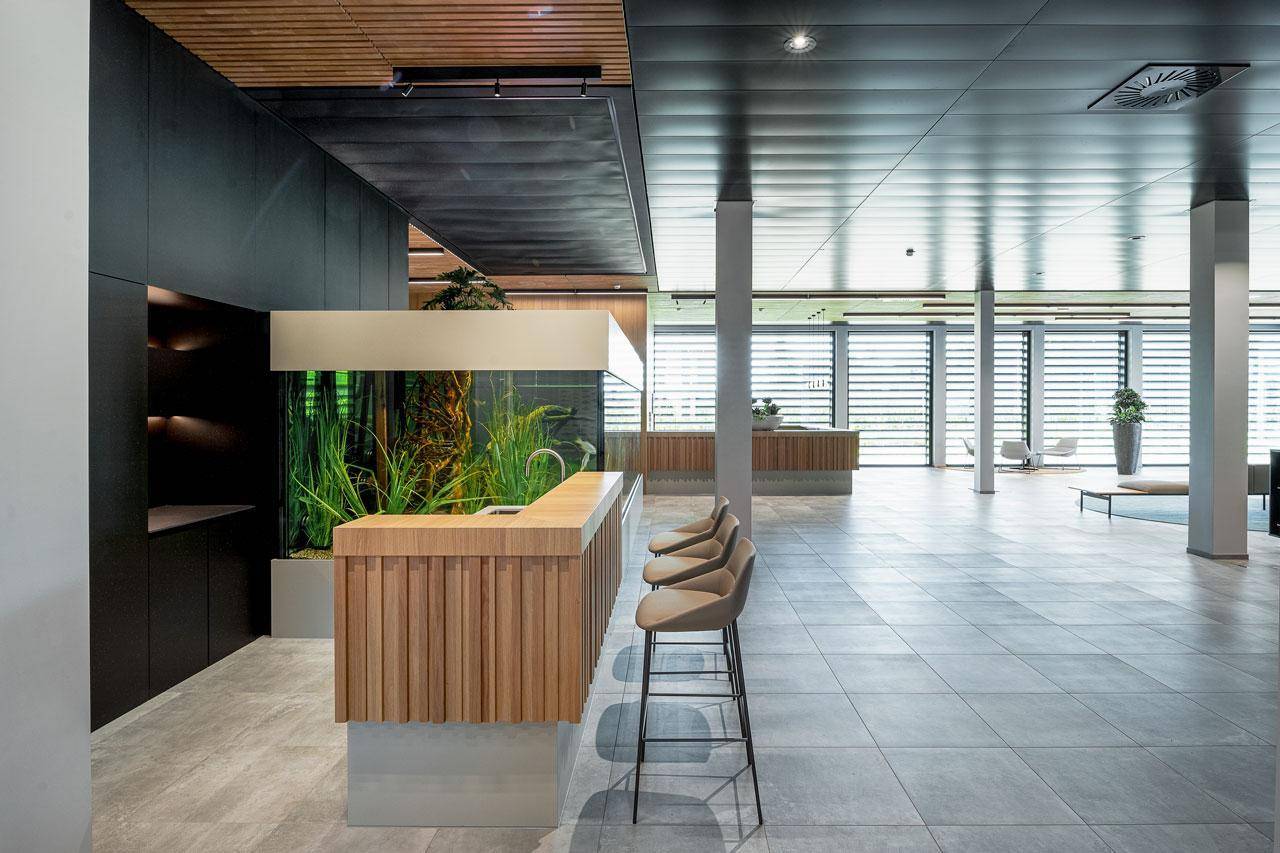 Moderner Empfangsbereich mit einer Bar, hohen Hockern und einem großen Aquarium als Blickfang.