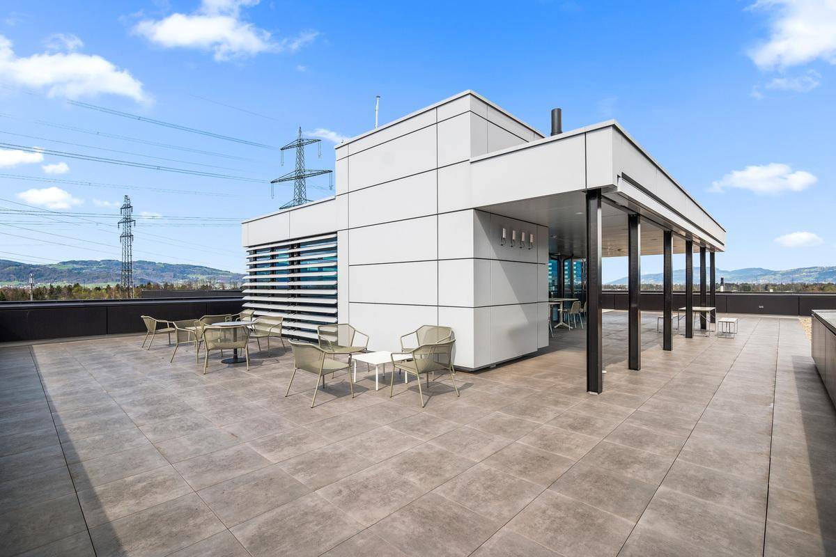 Geräumige Dachterrasse mit modernen Fliesen, Sitzgelegenheiten und einem überdachten Bereich mit Bergblick.