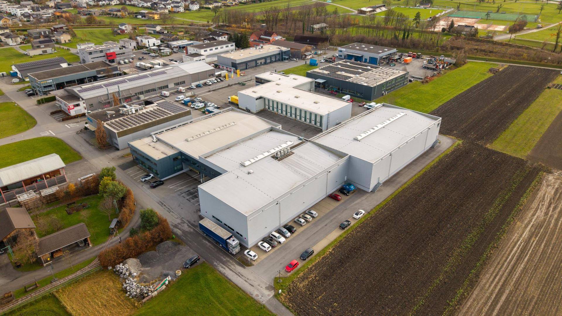 Weitläufige Luftaufnahme eines Industriegebiets mit mehreren Gebäuden und umliegenden landwirtschaftlichen Flächen.