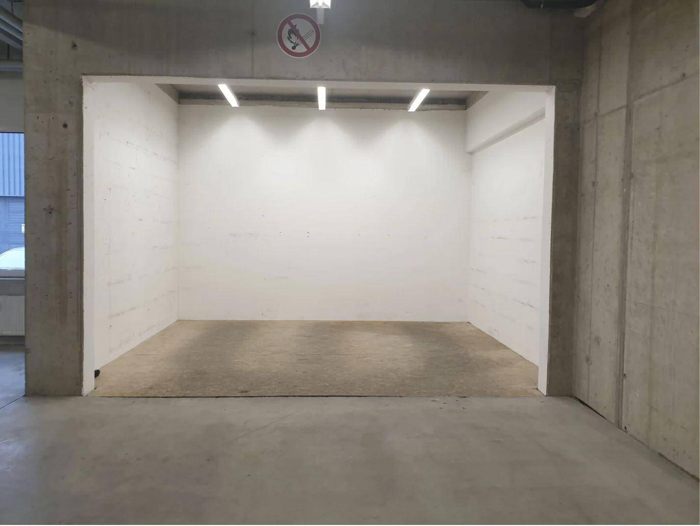 Leerer Lagerraum mit weißen Wänden und Betonboden in einem modernen Neubau.