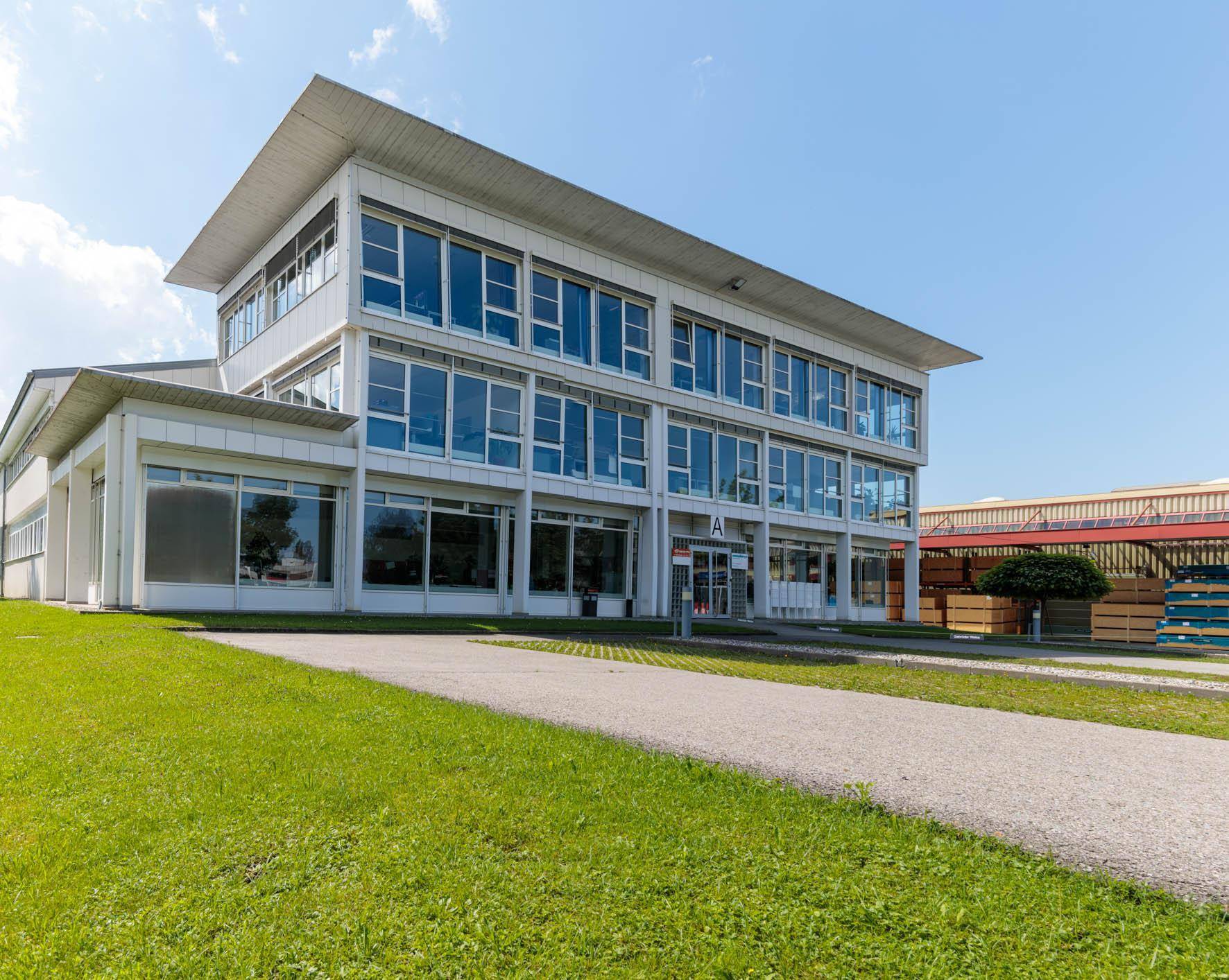 Ansicht des modernen Bürogebäudes von einer anderen Perspektive mit gepflegter Rasenfläche im Vordergrund.