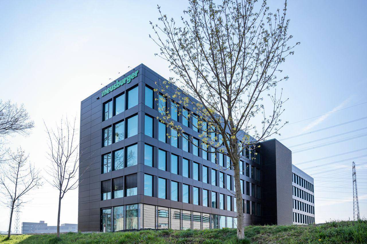 Modernes Bürogebäude mit dunkler Fassade und großen Glasflächen unter klarem Himmel.