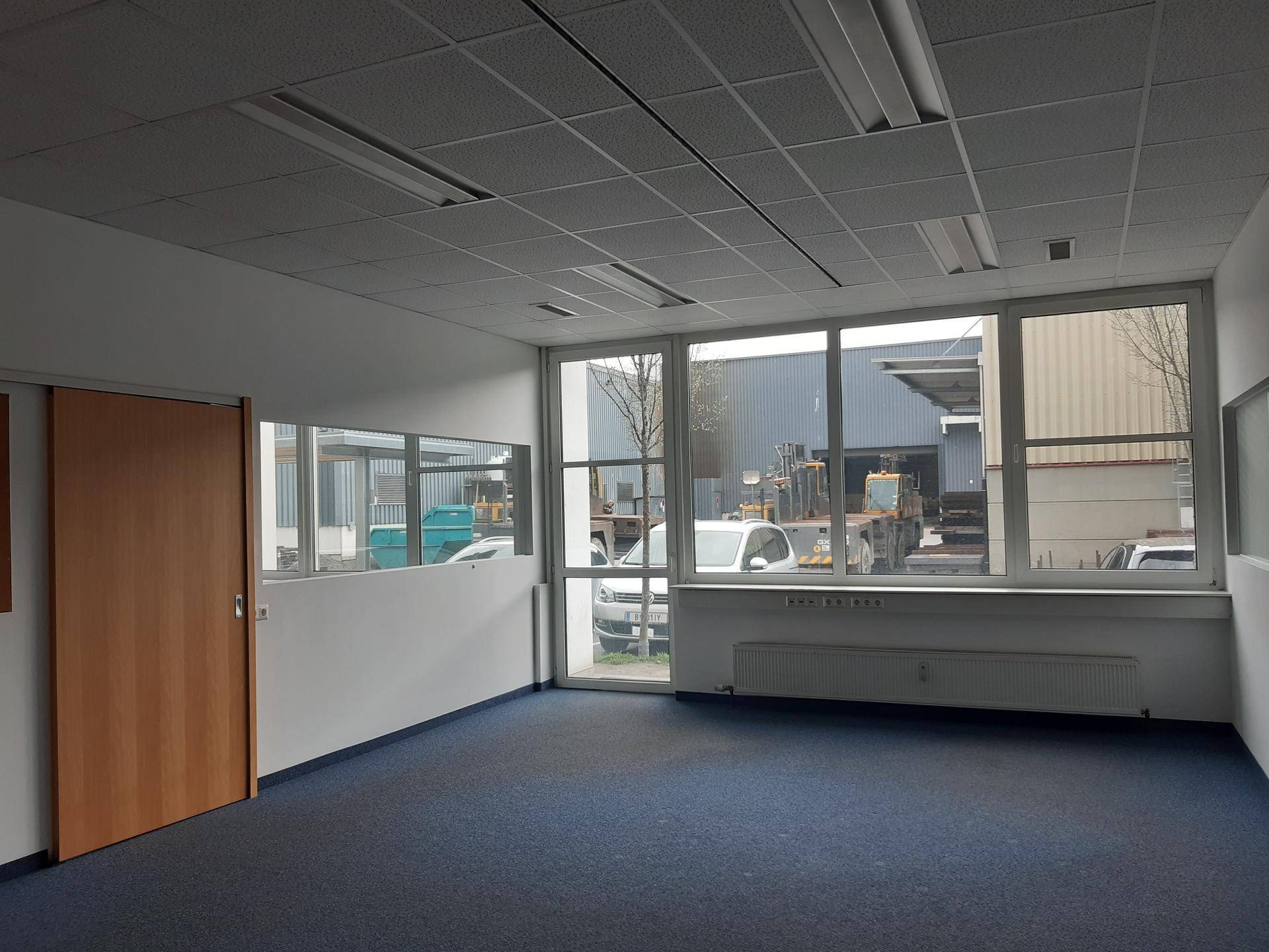 Geräumiges Büro mit großen Fenstern und einer Schiebetür aus Holz.