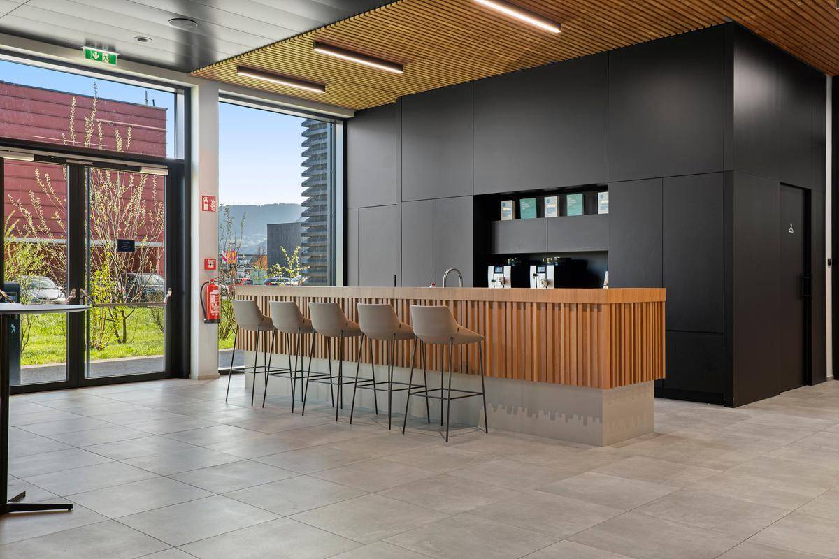 Moderne Küchenzeile mit Bar, hohen Hockern und großen Fenstern, die einen Blick nach draußen ermöglichen.