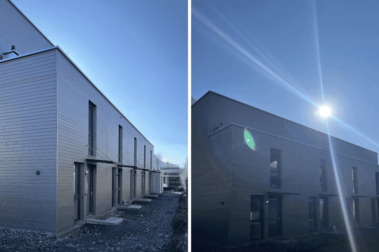 Moderne Reihenhäuser mit Holzfassade und großen Fenstern unter blauem Himmel.