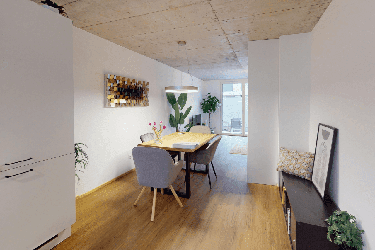 Essbereich mit Holztisch, modernen Stühlen und Zugang zum Wohnbereich.