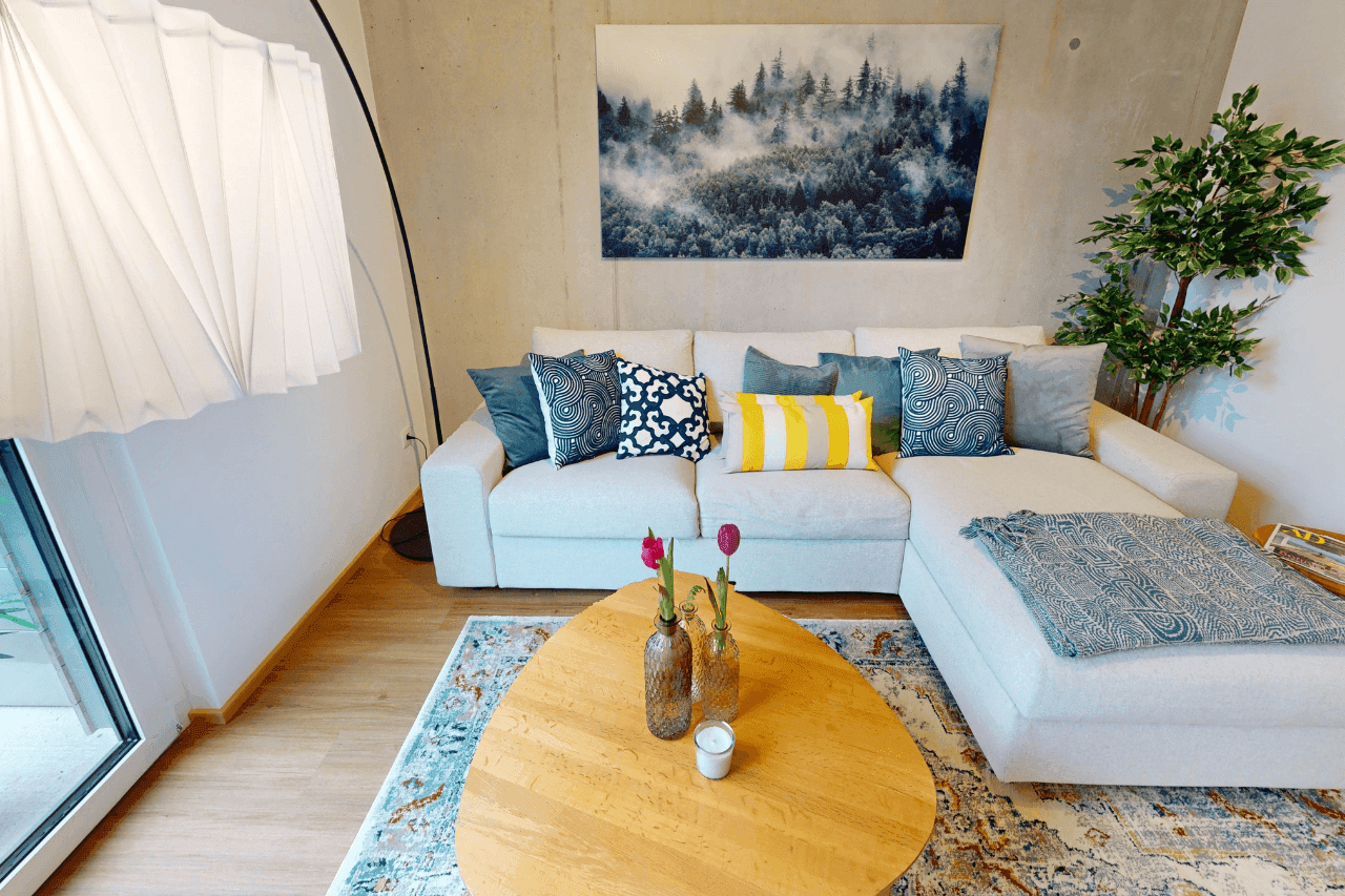 Gemütliches Wohnzimmer mit großem Ecksofa, Holzboden und moderner Dekoration sowie großen Fenstern.