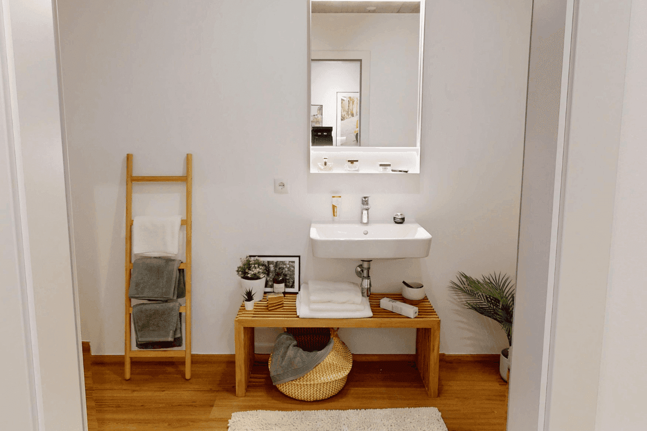 Modernes Badezimmer mit Waschbecken, Spiegel und Holzbank.
