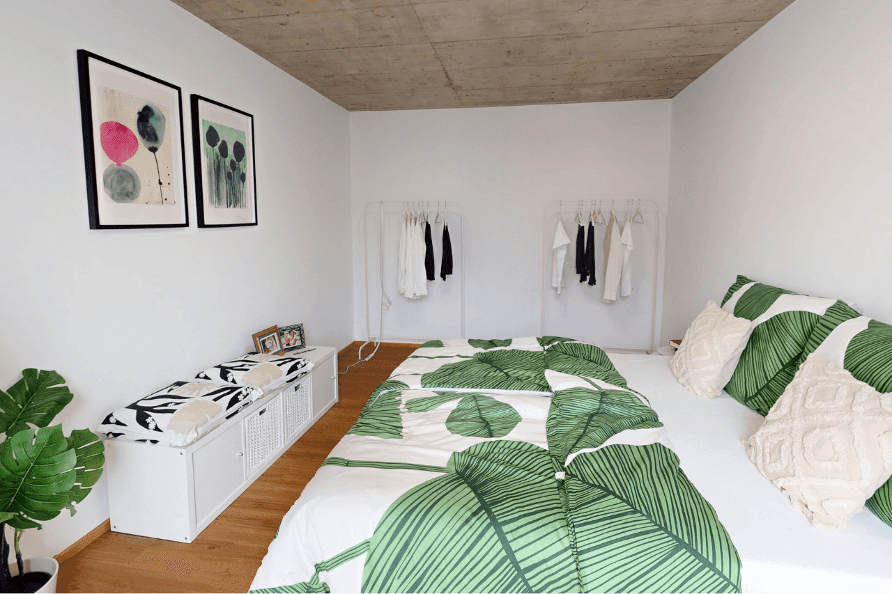 Schlafzimmer mit Doppelbett, minimalistischer Einrichtung und grünen Akzenten.