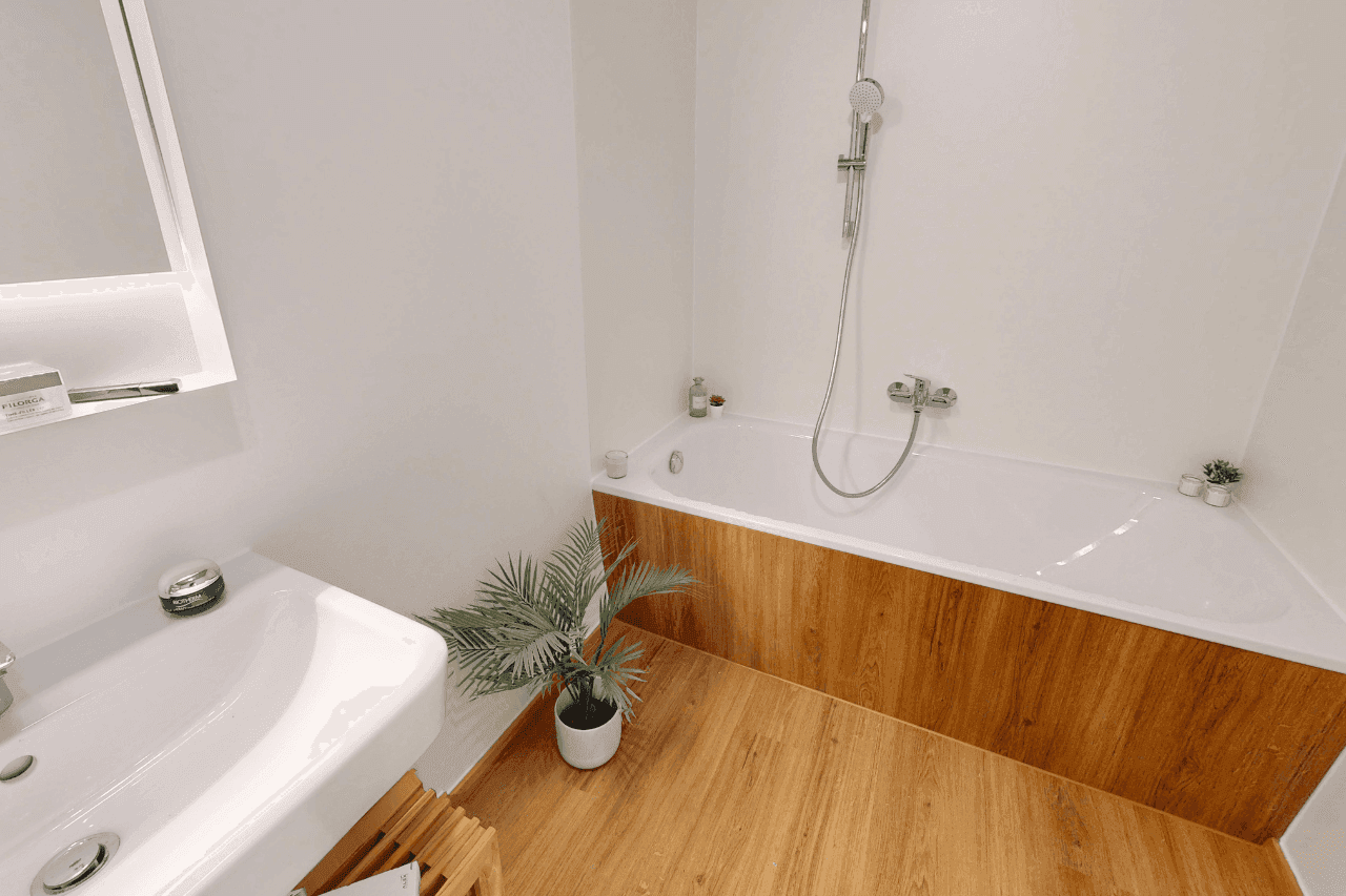 Modernes Badezimmer mit Badewanne, Holzboden und weißer Wandgestaltung.