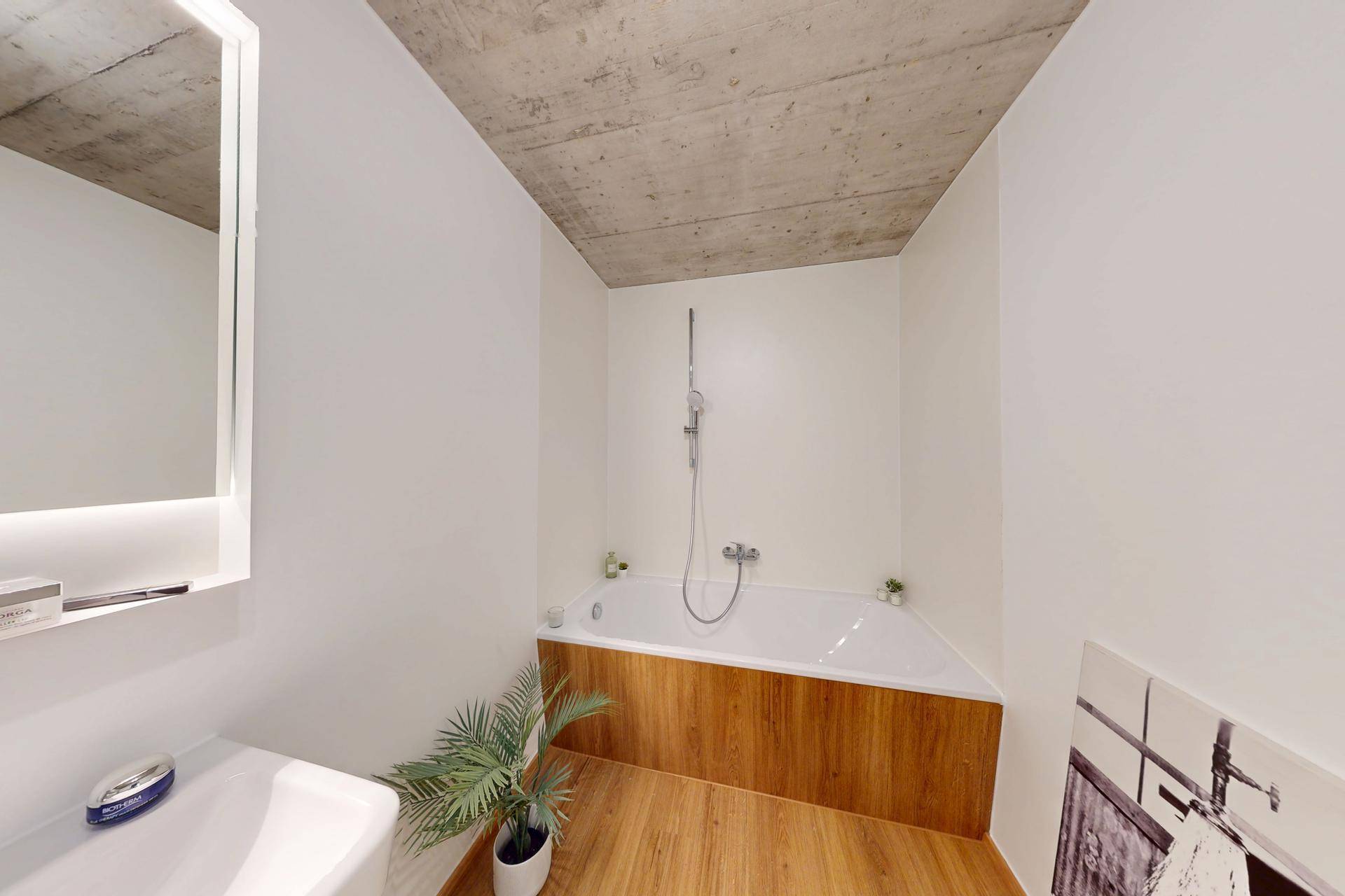 Badezimmer mit Badewanne, Holzboden und schlichtem Design.