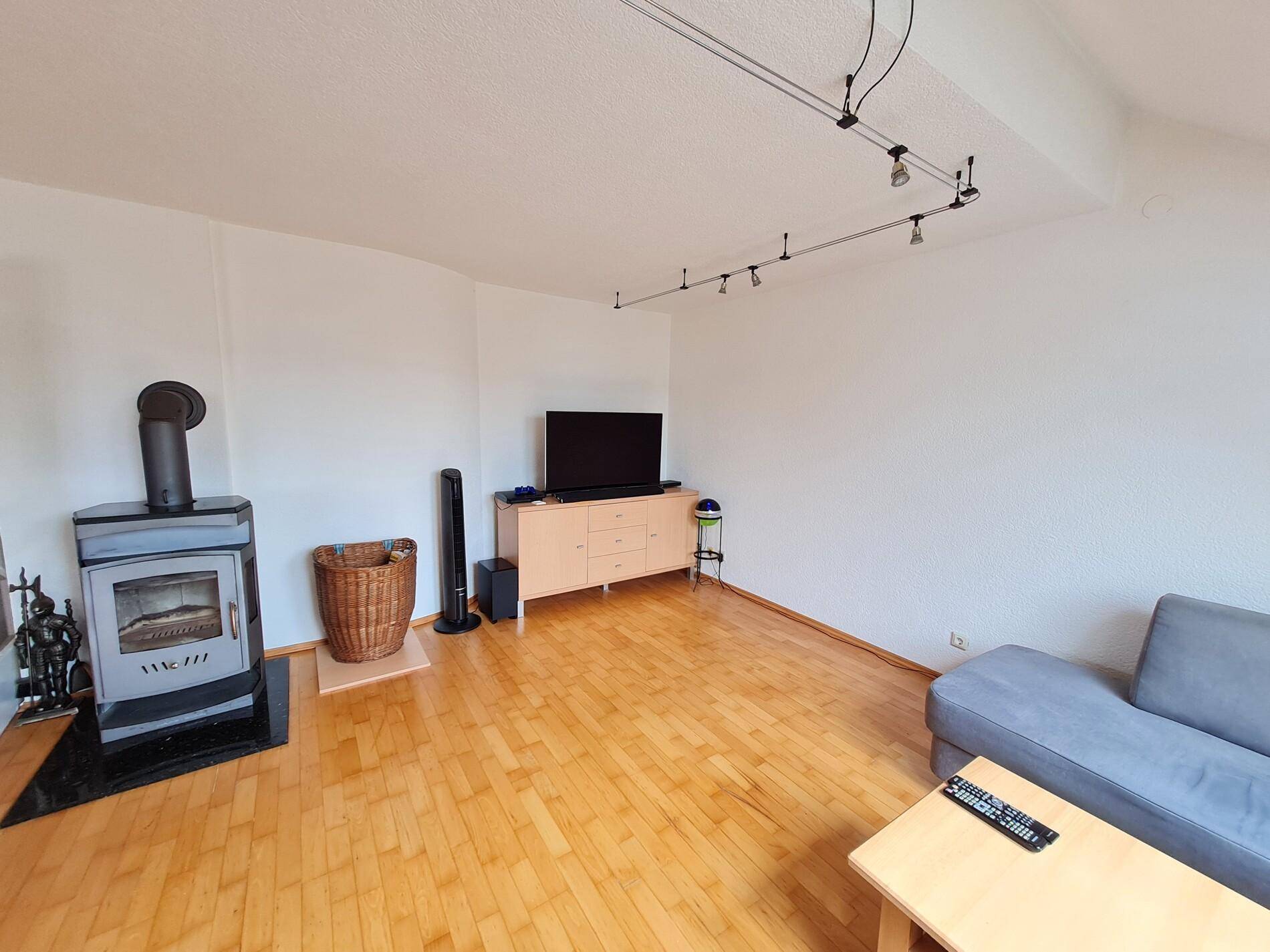 Heller Wohnbereich mit einem modernen Holzofen, Holzboden und ausreichend Platz für Unterhaltung.