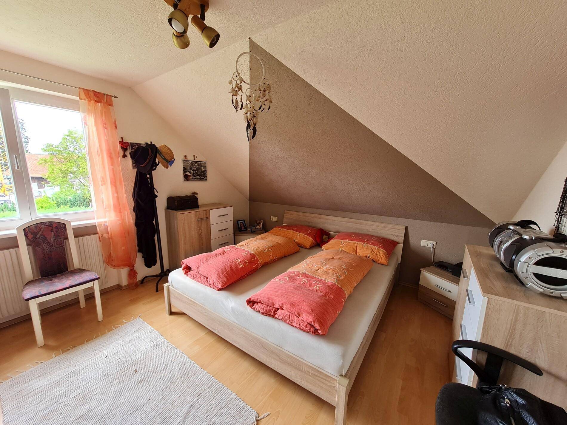 Gemütliches Schlafzimmer im Dachgeschoss mit Doppelbett, Fenster und Holzboden.