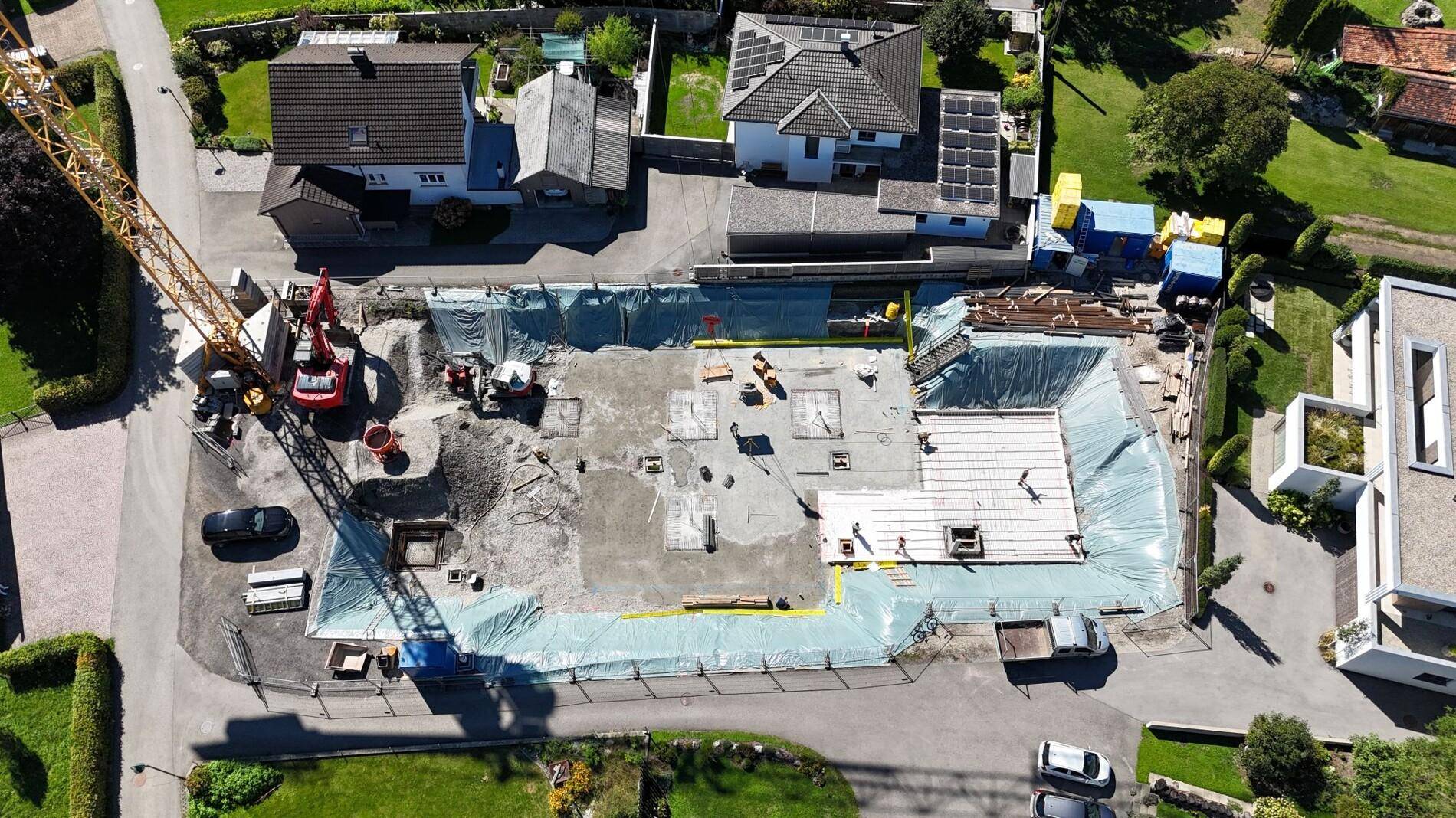 Luftaufnahme einer Baustelle mit ausgehobener Grube und beginnenden Fundamentarbeiten.