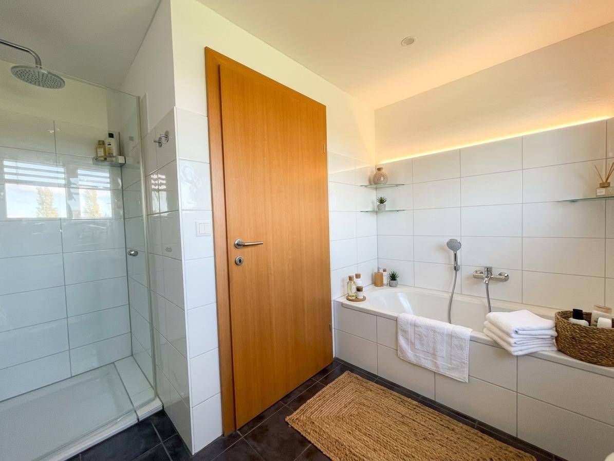 Modernes Badezimmer mit begehbarer Dusche, Badewanne und indirekter Beleuchtung.