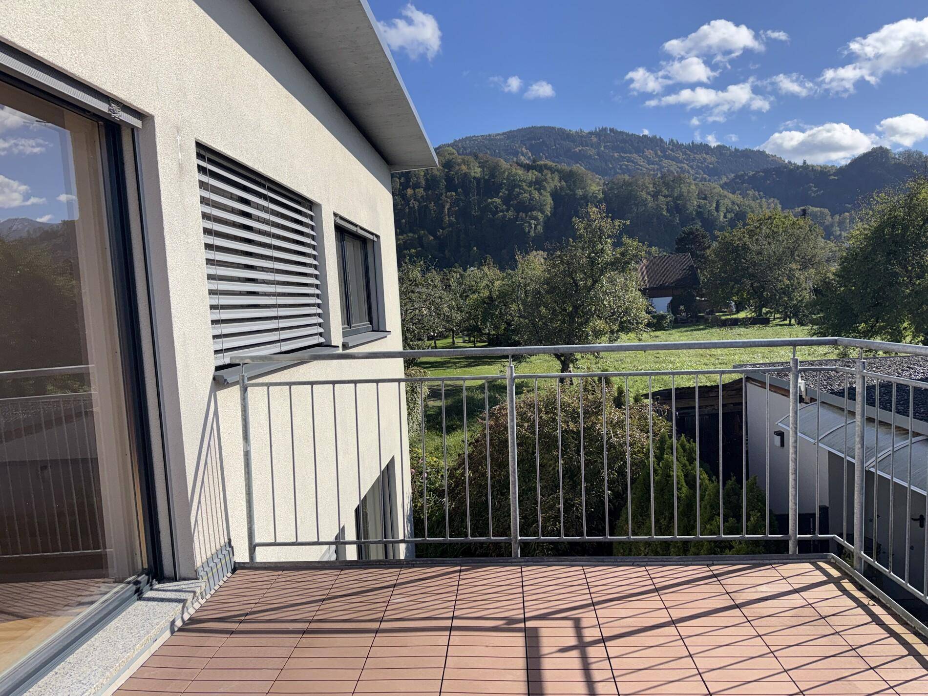Geräumiger Balkon mit Holzbodenfliesen und weitem Blick auf die umliegenden Berge.