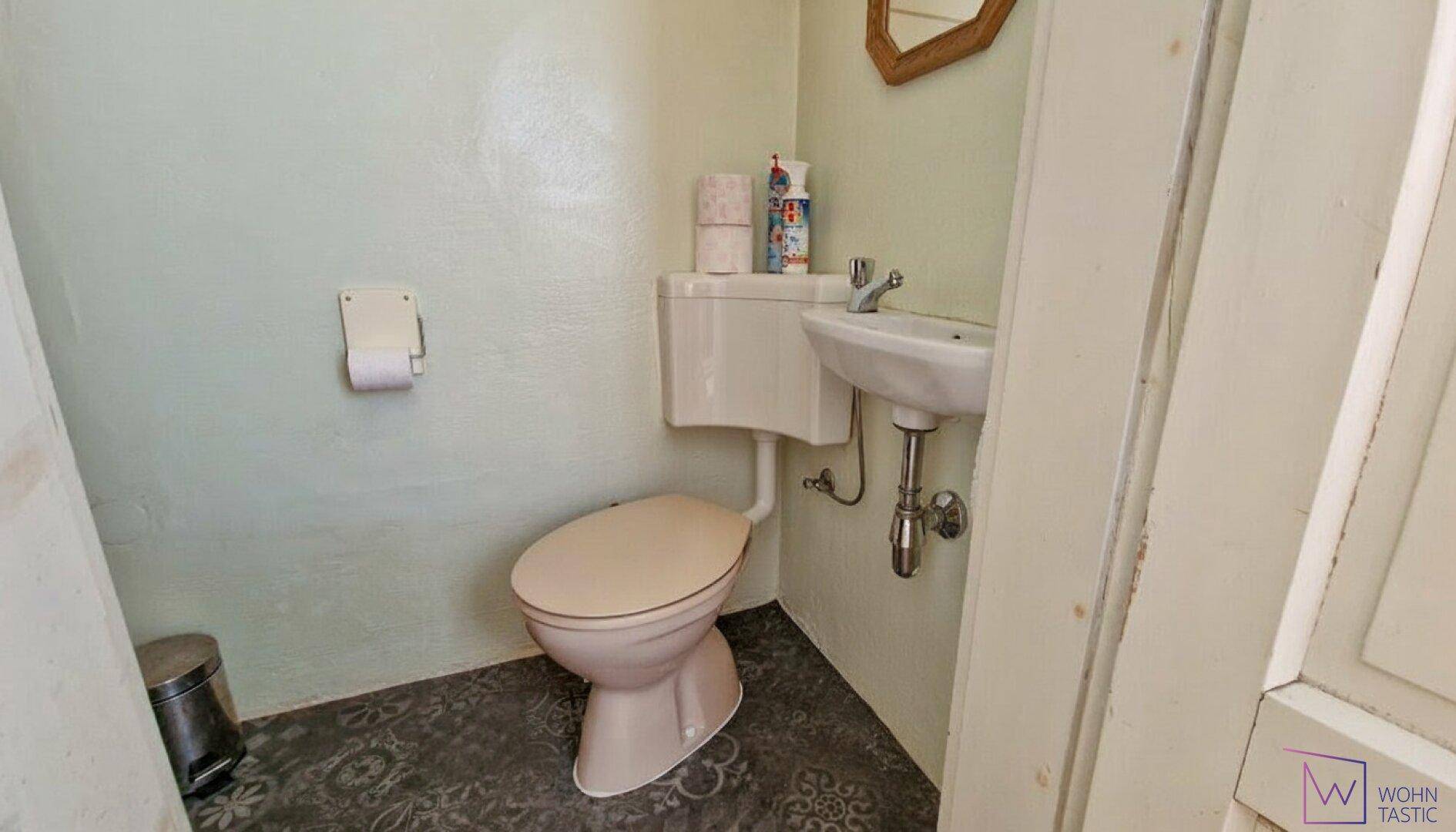 WC mit Fenster diskret hinter einer Tapetenwand.