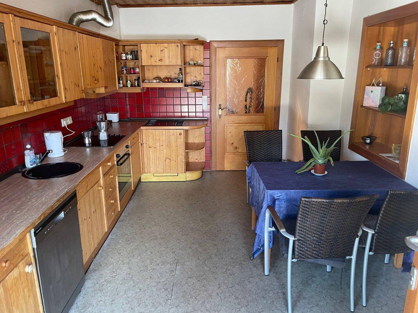 Rustikale Küche mit Holzschränken, roten Fliesen und einem Esstisch für gemeinsame Mahlzeiten.