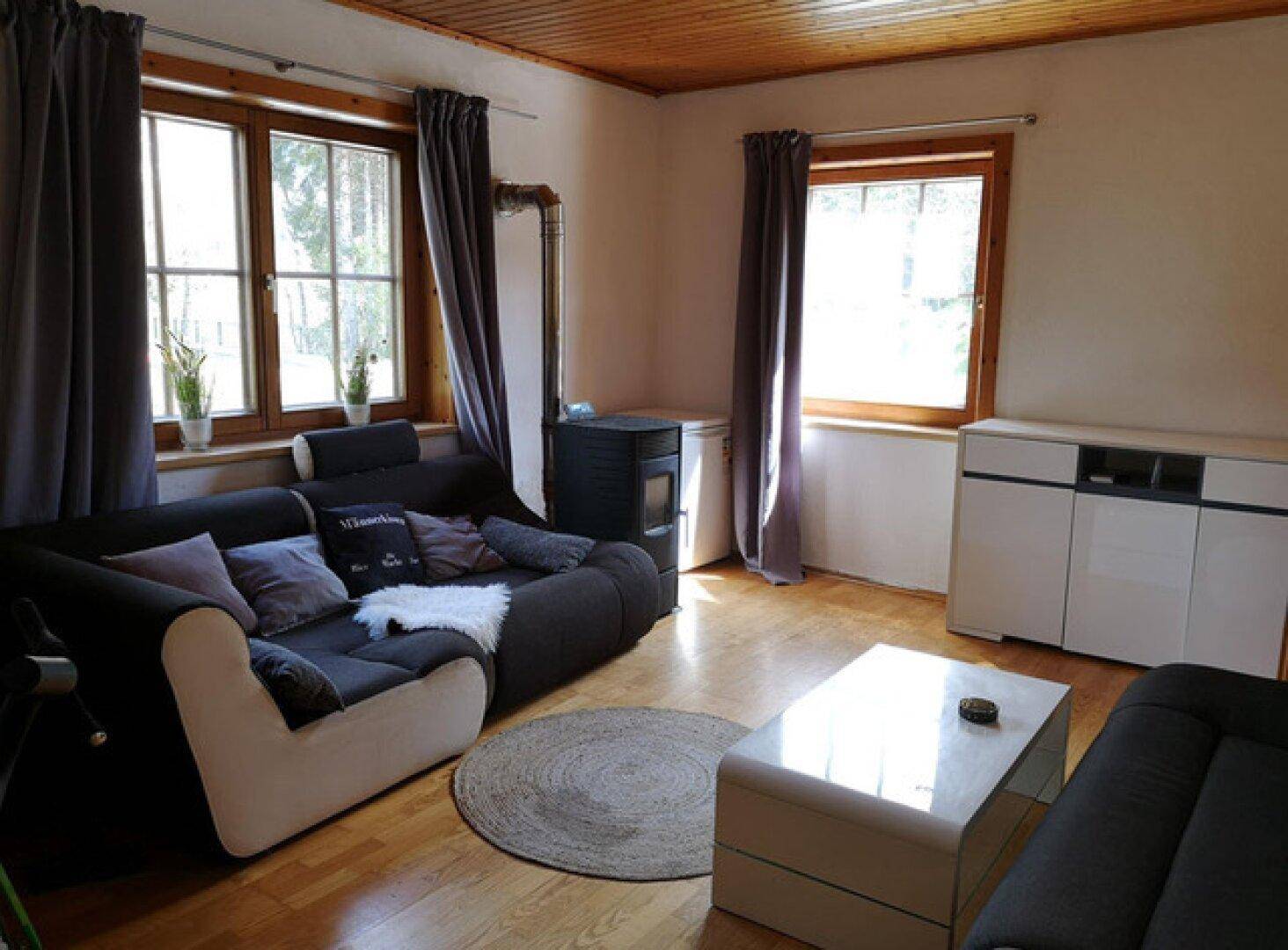 Gemütliches Wohnzimmer mit Holzboden, bequemer Couch und einem modernen Holzofen für Wärme.