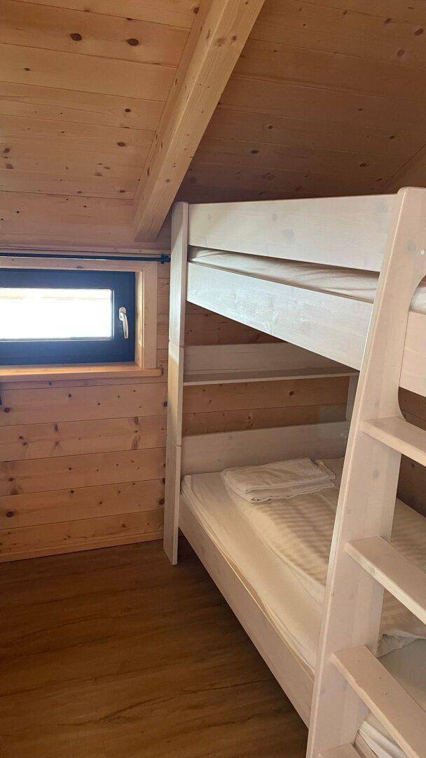 Gemütliches Schlafzimmer mit Holzwänden und einem Etagenbett, perfekt für Kinder oder zusätzliche Gäste.
